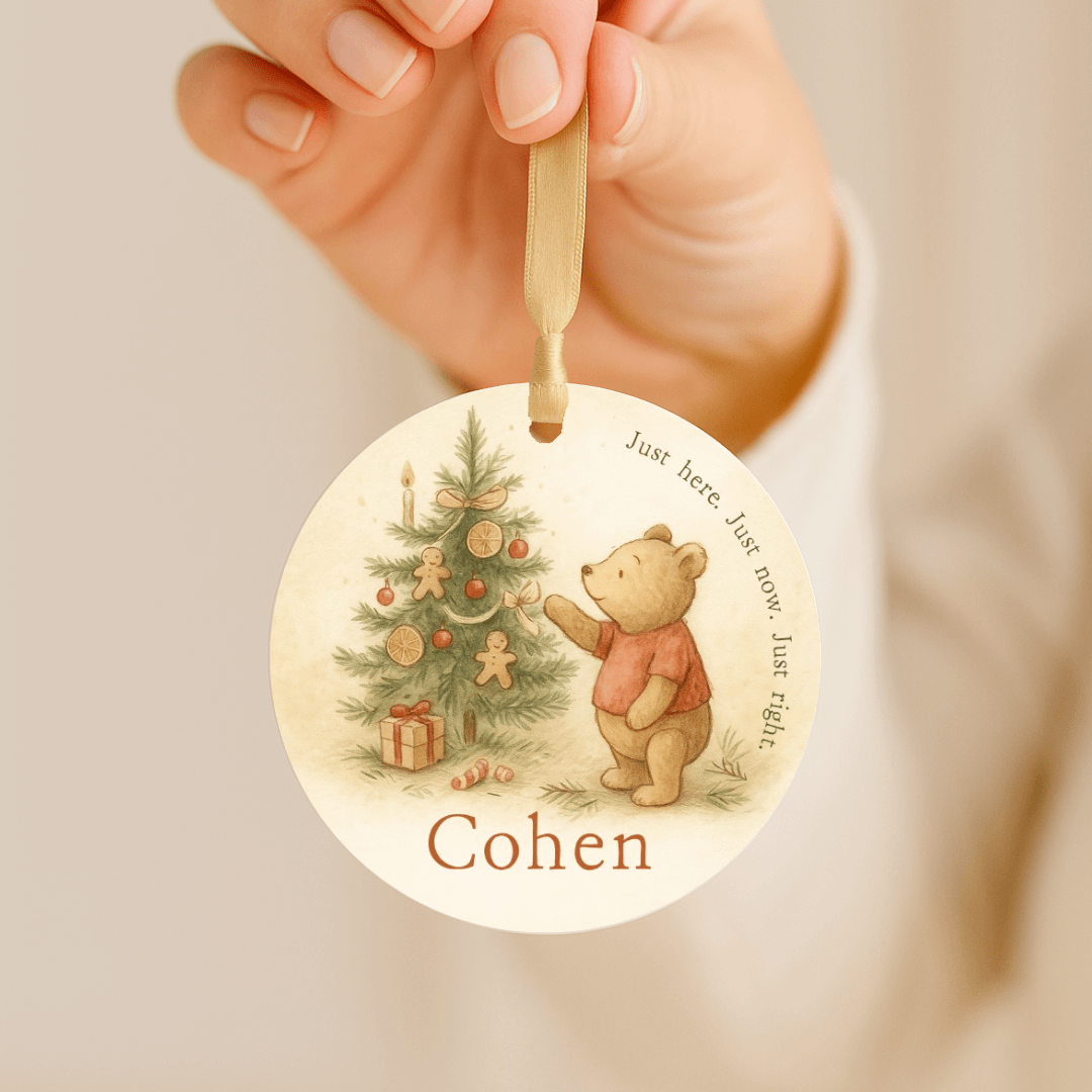 Storybook ornament with a bear and Christmas tree being held by a gold ribbon
