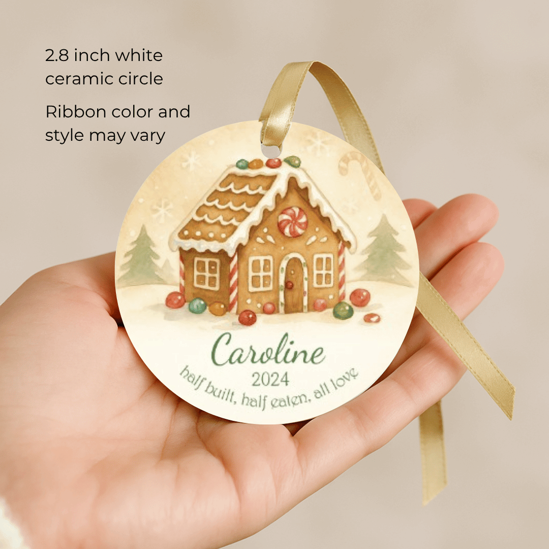 Round ceramic ornament with gingerbread house design held in a hand, against a beige background.