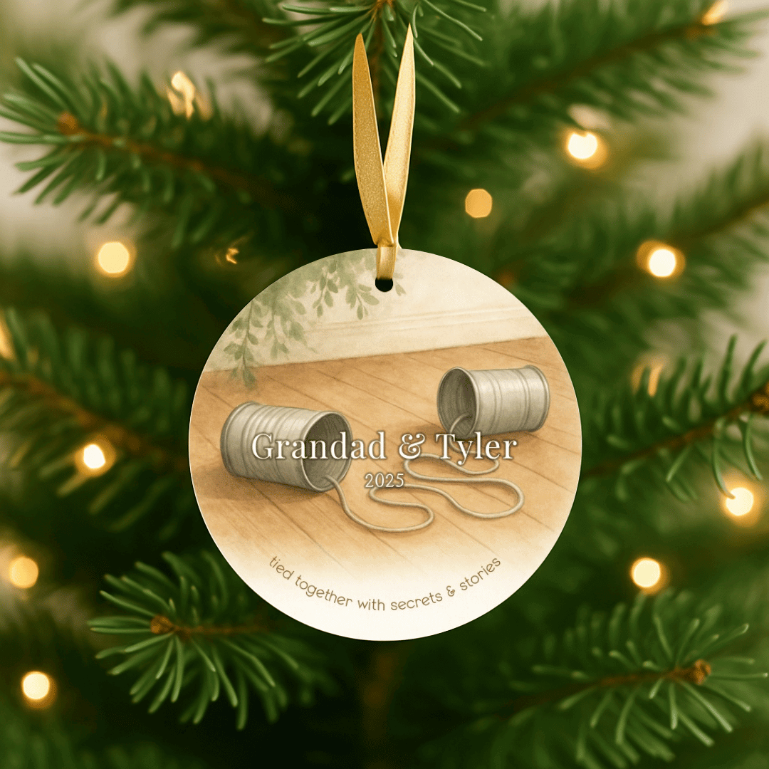 Personalized ceramic Christmas ornament with tin can phones for grandpa and a grandchild, hanging on a Christmas tree