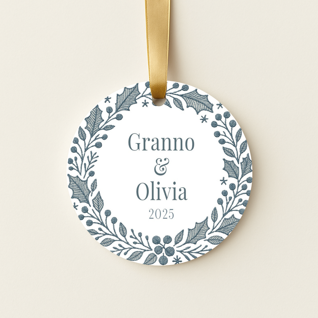 Round personalized ceramic Christmas ornament with a blue embroidered wreath design