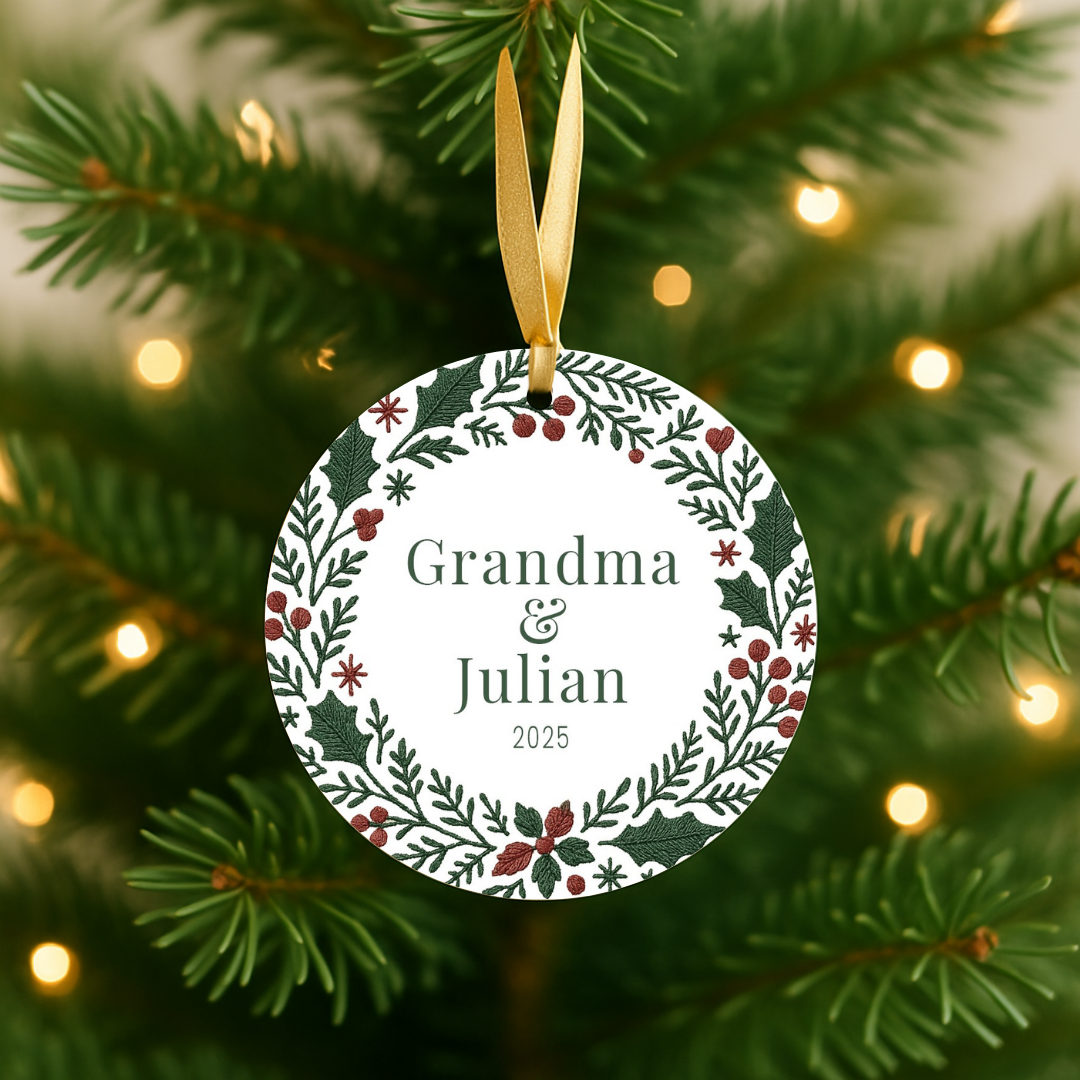 Round personalized Christmas ornament with a green and red embroidered wreath design hanging in a tree