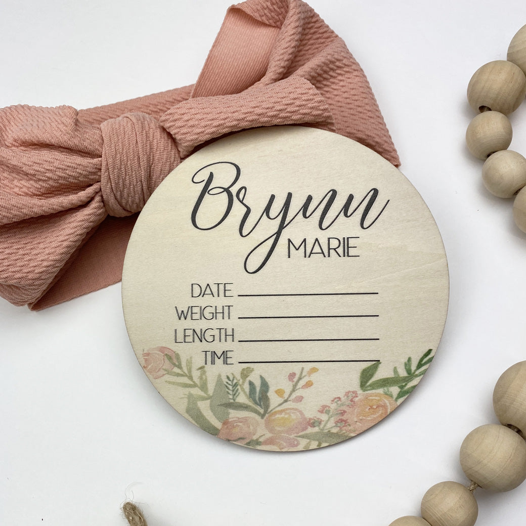 Floral design on a wooden circle, personalized with baby's name, to record the date, weight, length, and time of birth