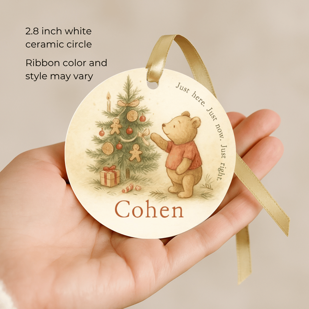 Round ceramic ornament with a bear and Christmas tree design, held in a hand.