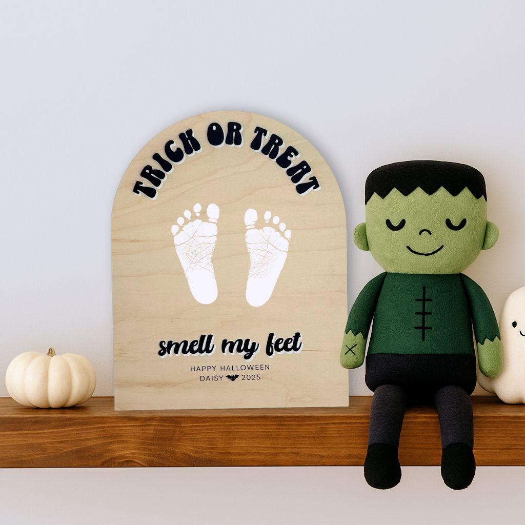 Trick or treat halloween footprint keepsake sign next to Frankenstein on a shelf