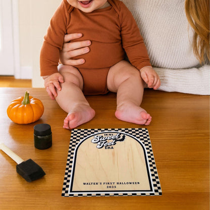 Baby sitting near his personalized Halloween footprint keepsake sign