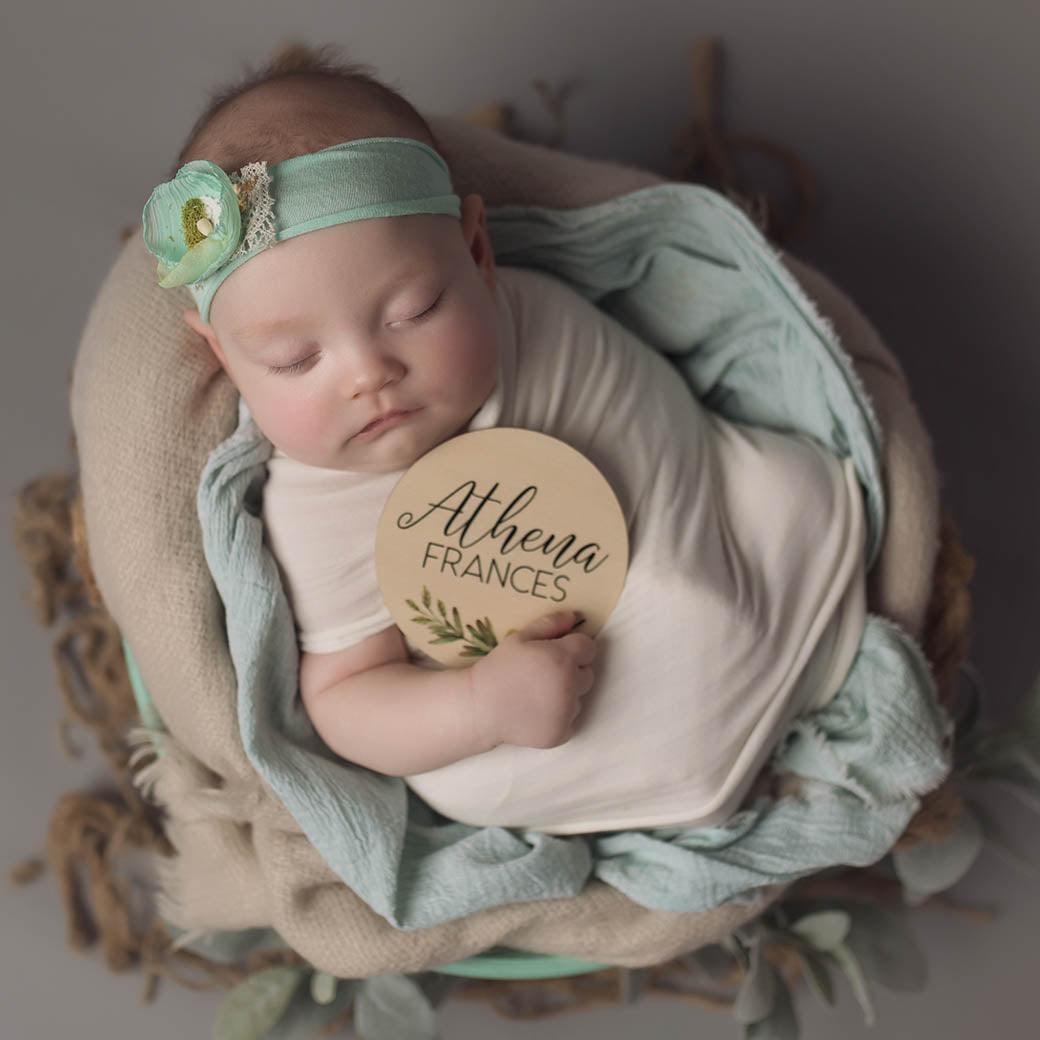 Sleeping baby holding name announcement sign