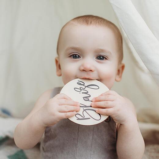 Baby boy holding botanical baby milestone name card