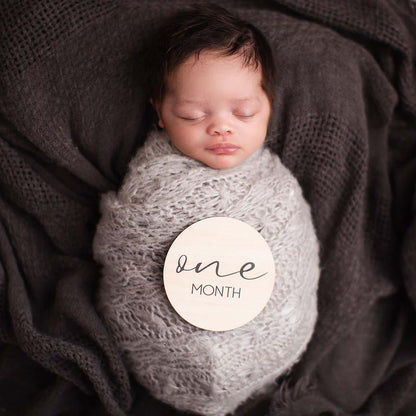 Sleeping baby with milestone cards at 1 month