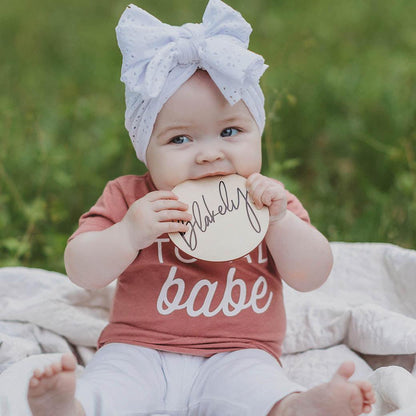 Baby girl holding milestone name card