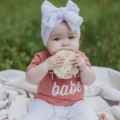 Baby girl holding 7 month orchid milestone card