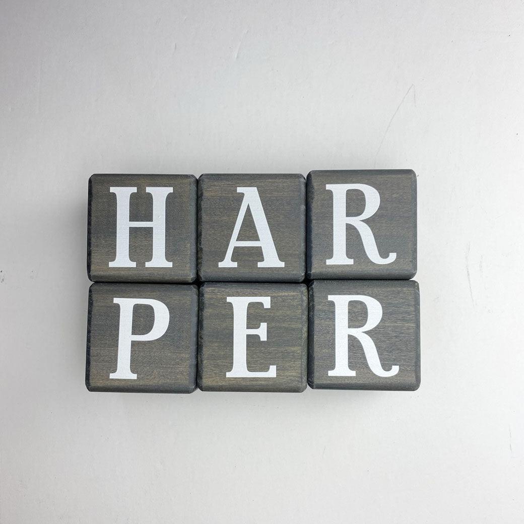 Wooden letter blocks in dark gray spelling Harper