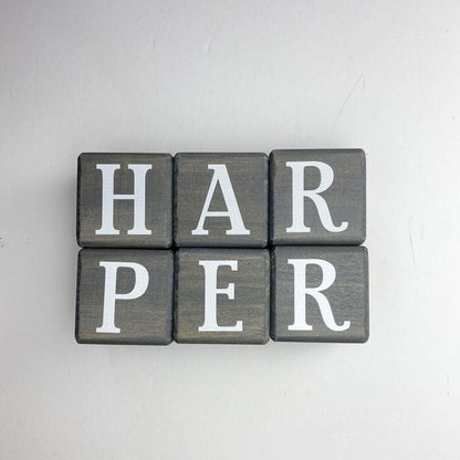 Wooden letter blocks in dark gray spelling Harper